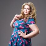 Plus size fashion model in floral dress, fat woman on gray background